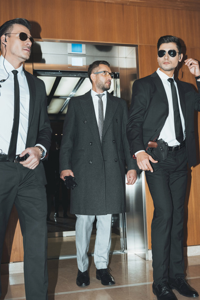businessman going out from elevator with two bodyguards - Photo, Image