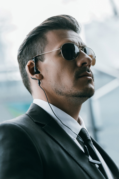 portrait of handsome security guard in sunglasses and security earpiece - Fotografie, Obrázek