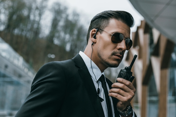 serious handsome security guard talking by portable radio - Photo, Image