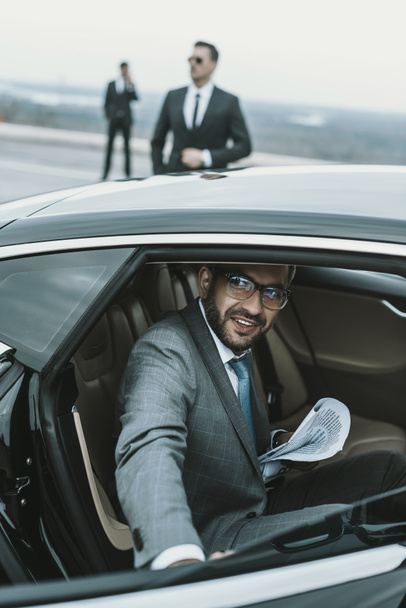 smiling businessman in glasses going out from car - Foto, Imagem