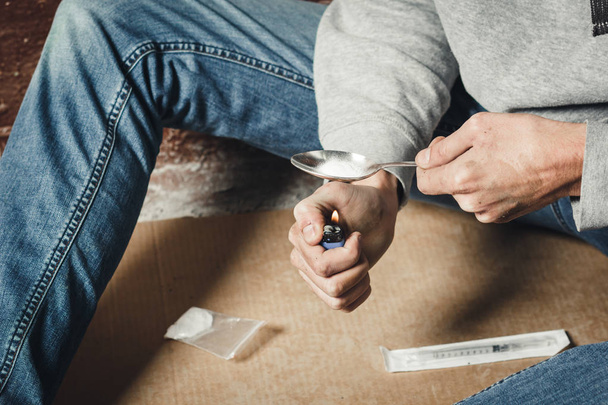 Las manos de un drogadicto que derrite cocaína en una cuchara. Un hombre hol
 - Foto, Imagen