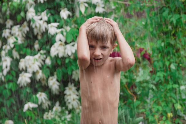 Веселый, взволнованный ребенок веселится, мокрый под дождем
 - Фото, изображение