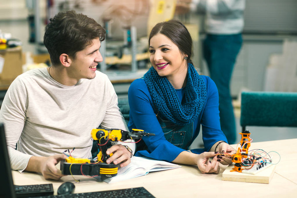 jóvenes estudiantes felices preparando robot para la prueba en el taller
 - Foto, Imagen