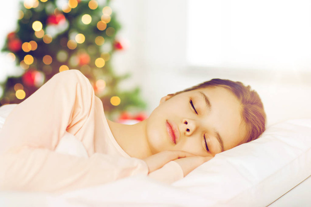 Mädchen schläft im Bett über Weihnachtsbaum - Foto, Bild