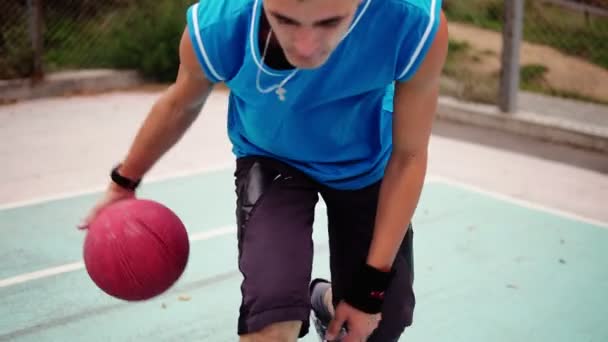 Closeup view of a young man practicing basketball outside. Slowmotion shot - Video