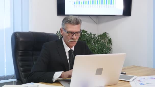Senior man speaks with white smartphone in office - Imágenes, Vídeo