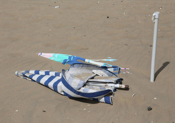 Солнечные зонтики на пляже затоплены песком после торнадо
 - Фото, изображение