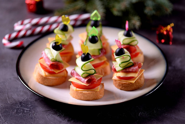 Canap on skewer from bread baguette with toast cheese, sausage, tomato, cucumber and olives. Traditional snack for the New Year. - Photo, Image