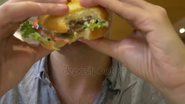 člověk jíst hamburger. detail. kotletu sendvič. 4k - Záběry, video
