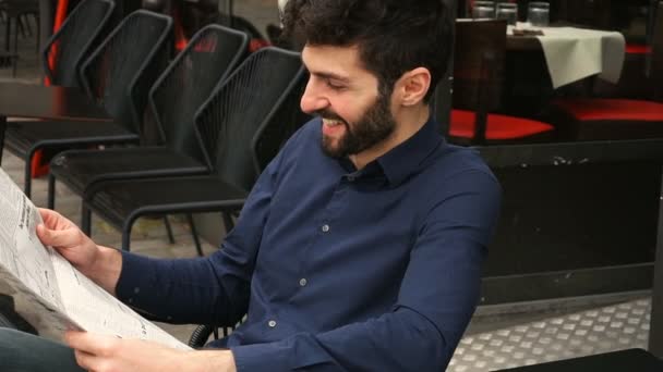 Journalist liest Zeitungsartikel in Zeitlupe in Großaufnahme am Cafétisch. - Filmmaterial, Video
