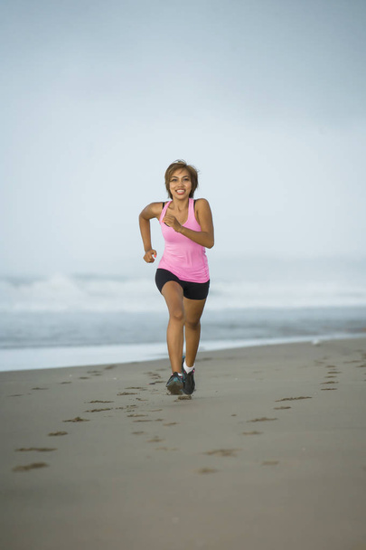 mladý atraktivní a fit asijské sport runner žena běží na pláž moře straně usmíval se šťastný v péči o tělo fitness  - Fotografie, Obrázek