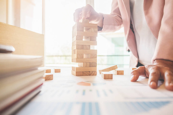 Hand of business man planning, risk and strategy in business.Businessman gambling placing wooden block on a tower. - 写真・画像