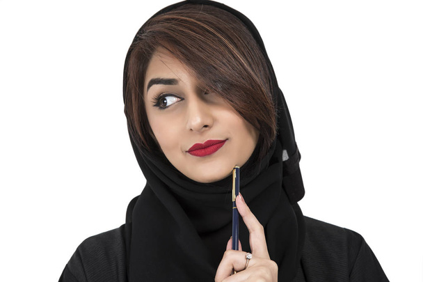 Portret arabskich młode kobiety uśmiechający się trzymając pióro i myśli - Zdjęcie, obraz