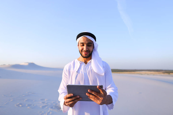 Arabian biznesmenem trzyma w ręce i korzysta z tabletu, s - Zdjęcie, obraz