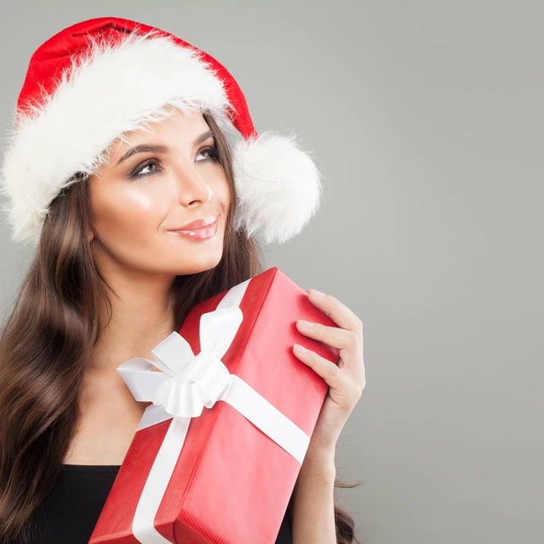 Femme de Noël à Santa Hat avec boîte cadeau de Noël rouge levant les yeux
 - Photo, image