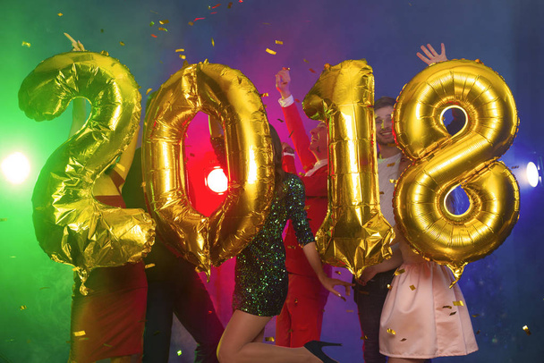 The composition of the golden balloons in the form of figures on a background of a dancing group of young people. The new year 2018. Festive New Year party or disco. - Fotoğraf, Görsel