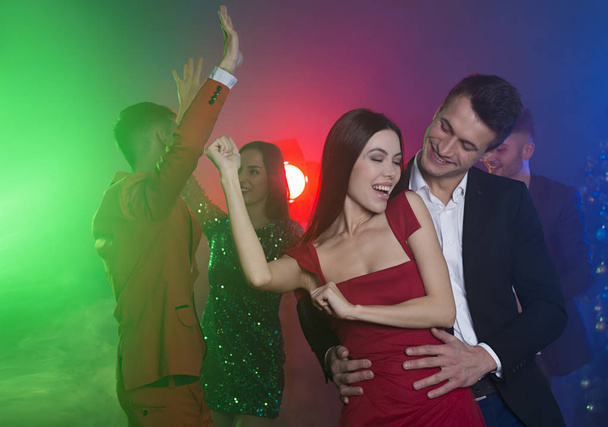 Group of young cheerful and happy friends are dancing at a party. Man and woman dancing in the foreground in front of the camera - Photo, Image
