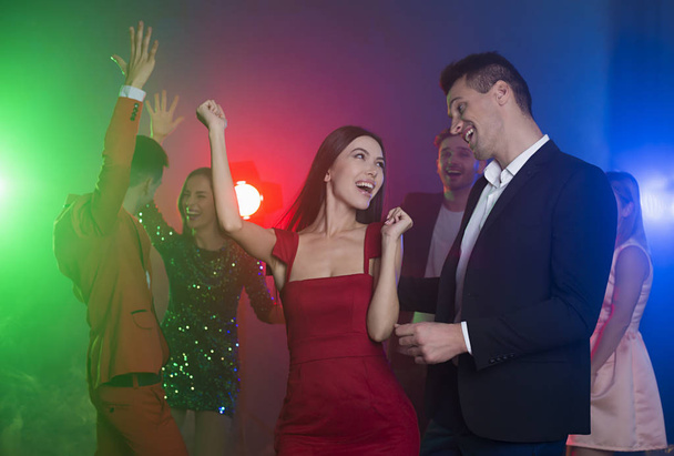 Ομάδα νέων χορεύουν χαρούμενος και ευτυχισμένος φίλους σε ένα πάρτι. Άνδρας και γυναίκα χορεύει στο προσκήνιο μπροστά από την κάμερα - Φωτογραφία, εικόνα