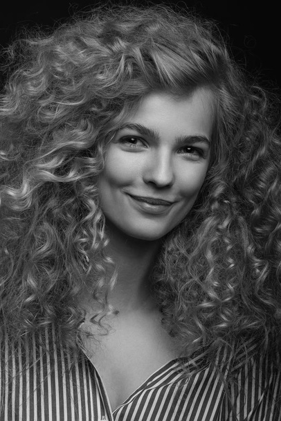 Emotive black and white studio portrait of cute young woman with curly hair. - 写真・画像