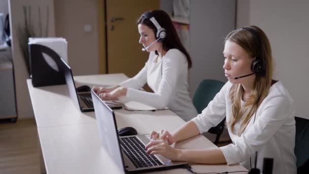 Several women print the text on the laptop keyboard, the ladies talk on the microphone in the call center office, they answer incoming calls and advise customers - Footage, Video