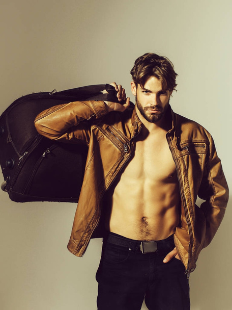 muscular bearded man with sexy body holds big bag, suitcase - Fotoğraf, Görsel