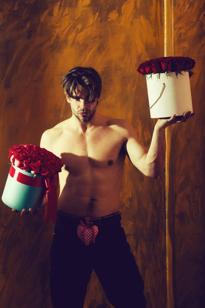 bearded muscular man with sexy body holds red rose box - Photo, Image