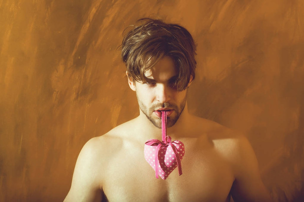 bearded muscular man with sexy body holds pink valentines heart - Zdjęcie, obraz