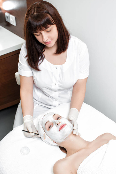 beautician applies mask to the face of  woman - Foto, Imagem