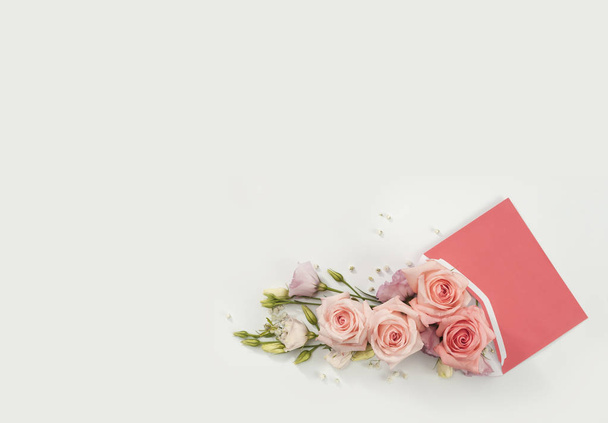 花の配達から贈り物として封筒から出てくるピンクのバラ - 写真・画像