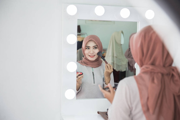 woman with hijab applying makeup. - Zdjęcie, obraz