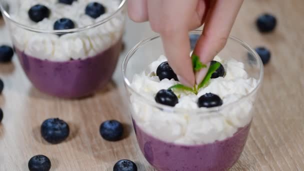 Decorate with mint leaves blueberry Panna cotta in a glass - Кадры, видео