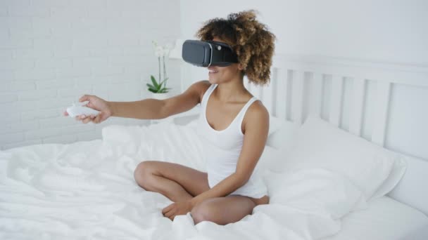 Smiling woman in VR glasses on bed - Кадры, видео