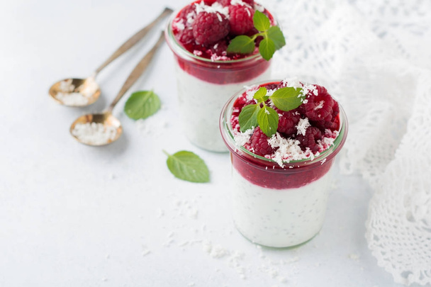 Layered raspberry smoothies with chia seeds, fresh raspberry and coconut on a light stone background. Useful dessert. Selective focus. - Фото, зображення