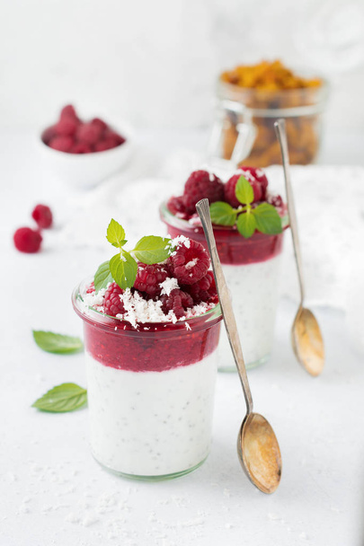 Layered raspberry smoothies with chia seeds, fresh raspberry and coconut on a light stone background. Useful dessert. Selective focus. - Фото, зображення