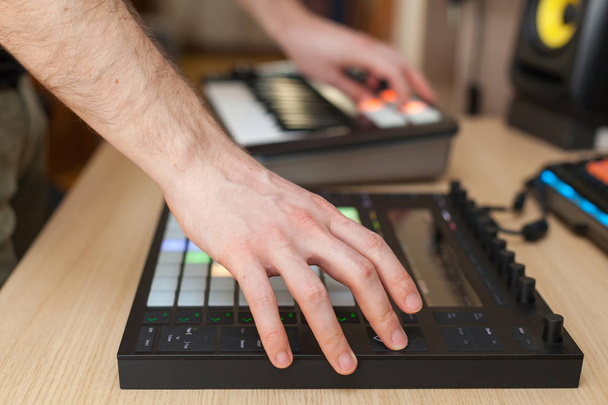 Productor hace una música en controlador de producción profesional con pulsadores
 - Foto, Imagen