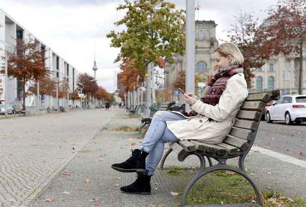 beautiful young woman with smartphone sitting on bench - Photo, Image