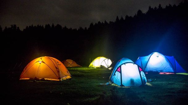 Iluminação acampamento tendas com floresta no fundo
 - Foto, Imagem