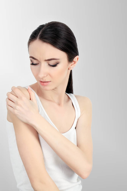 Азіатський жінка з біль в шиї і плеча над сірий backgro - Фото, зображення