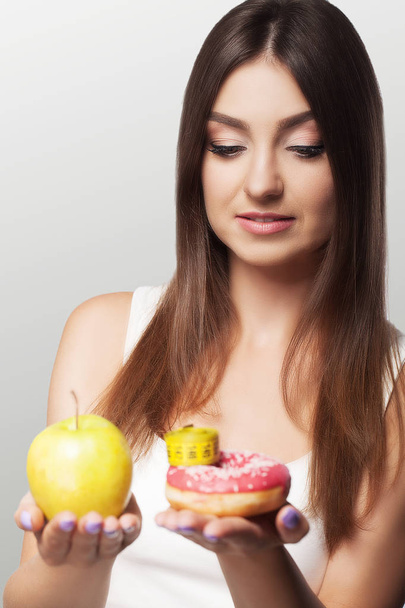 Een jonge vrouw maakt een keuze tussen gezonde en schadelijke voedsel. S - Foto, afbeelding
