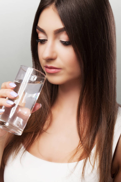 Пейте воду. Молодая девушка пьет воду из стакана. Ежедневный ват
 - Фото, изображение