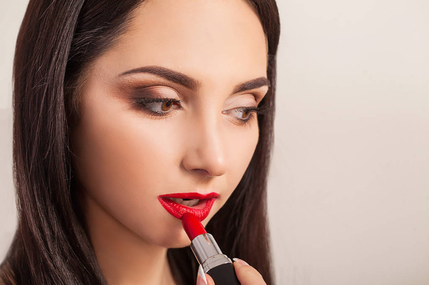 Beautiful woman paints lips with lipstick. Beautiful woman face. - Photo, Image