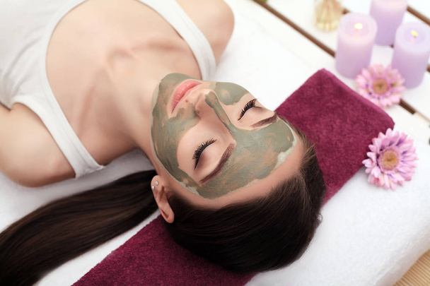 Wellnesstherapie für junge Frau mit Gesichtsmaske im Schönheitssalon - - Foto, Bild