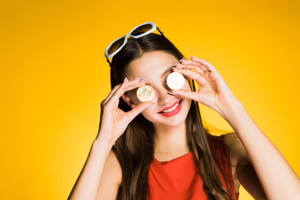 smiling young girl holding golden bitcoins in her hands, knows the sense in the crypto currency - Fotografie, Obrázek