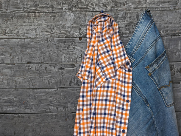 Camisa a cuadros y jeans en pared de madera vintage
. - Foto, Imagen
