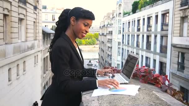 halb afrikanische Geschäftsfrau arbeitet mit Laptop auf Balkon. - Filmmaterial, Video