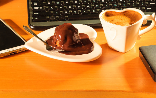 Cup of coffee and chocolate cake next to computer. - Foto, Imagem