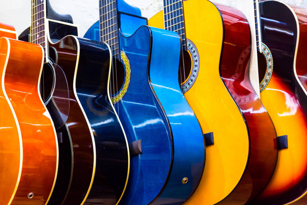  барвисті дерев'яні гітари, що звисають на стіні магазину шоурум
 - Фото, зображення