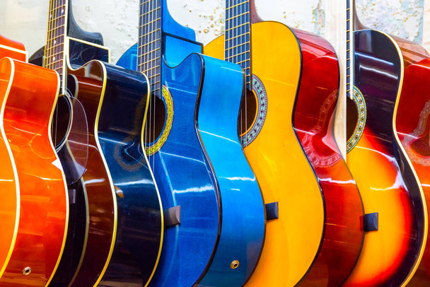  барвисті дерев'яні гітари, що звисають на стіні магазину шоурум
 - Фото, зображення