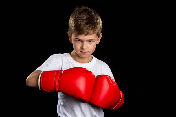A confident, angry boxer portrait with red boxing gloves together. The defend position portrait on the black background - Foto, afbeelding