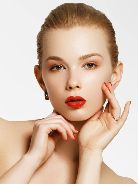 Makeup products. Young beautiful girl with gold earrings and ring smiling on white background. Red nails with manicure and white smile. Young woman with fashion accessories - Φωτογραφία, εικόνα